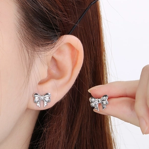 Boucles d'oreilles nœud papillon en acier inoxydable argenté portées par un mannequin