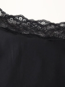 Dettaglio di un abito in raso nero con bordo in pizzo delicato sullo scollo