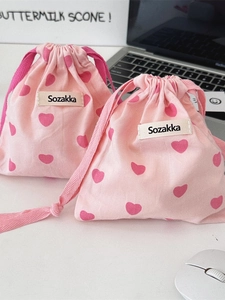 Set of pink canvas drawstring tote bags with heart patterns on a minimalist workspace