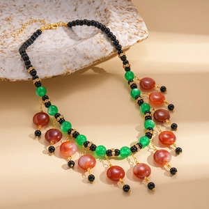 Bohemian beaded tassel necklace with colorful resin beads and gold accents on ceramic plate