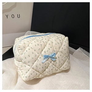Detailed macro of floral quilted cotton makeup bag with purple flowers and blue ribbon bow