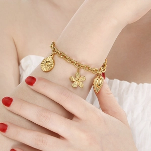 Golden summer beach bracelet with heart, flower, and round pendants on a textured chain