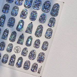 Macro shot of holographic Gothic stained glass nail stickers with butterfly and cross motifs
