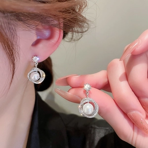 Detailed view of silver hoop earrings with white pearls and sparkling cubic zirconia stones