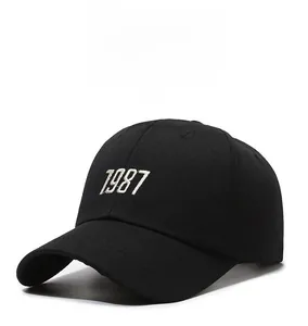 Detailed close-up of white 1987 embroidery on a black cotton baseball cap with ventilation holes