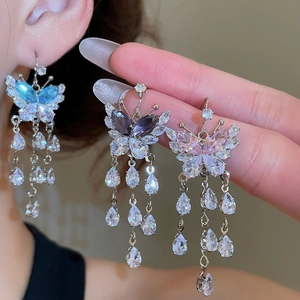 Macro shot of butterfly tassel earrings with drop zircon detail and light blue stones