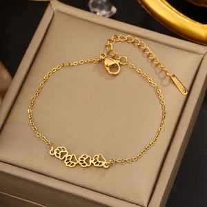 Detail of golden stainless steel bracelet with paw print charms and S.STEEL hallmark tag