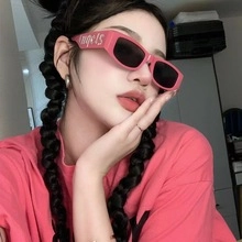 Detail of pink rectangular thick-framed sunglasses with dark lenses and Angels lettering
