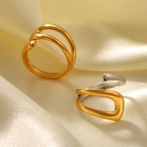 Minimalist bicolor and gold stainless steel open rings on elegant yellow silk background