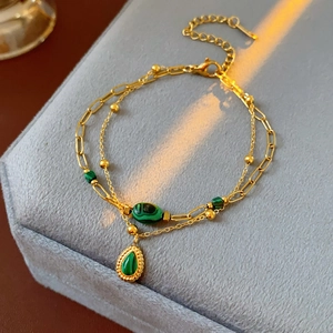 Détail d'un bracelet vintage doré à double chaîne avec malachite sur boîte à bijoux