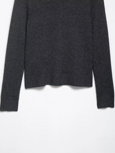 Detail of dark grey knit cardigan showing ribbed hem and sleeve cuffs craftsmanship
