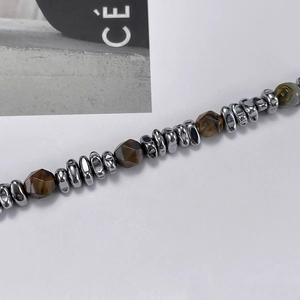 Detail view of tiger eye beads and polished steel chain link bracelet on a minimalist background
