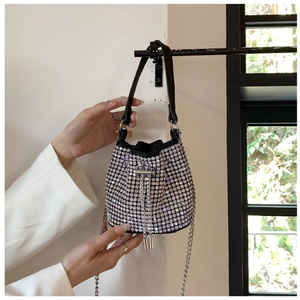 Detail of silver rhinestone bucket bag featuring a black handle and chain drawstring