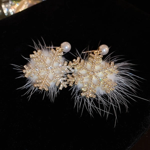 Macro view of gold snowflake earrings with sparkling rhinestones and soft white flocking
