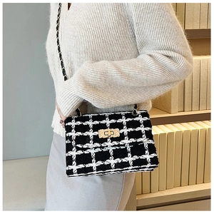 Detail of tweed crossbody bag with black and white check pattern and gold chain strap