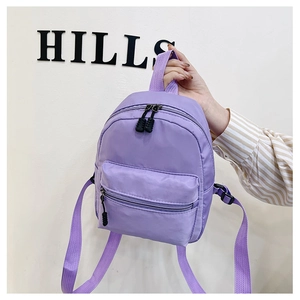Close-up of purple nylon mini backpack held by hand featuring front zipper pocket