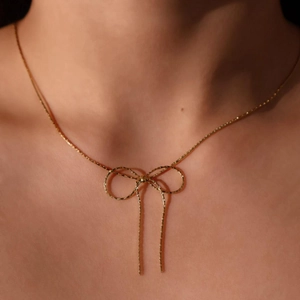 Elegant gold bow pendant necklace on model's neck, minimalist stainless steel chain