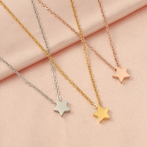 Detailed close-up of star pendants in silver, gold, and rose gold on pink satin fabric
