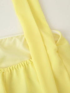 Detailed close-up of yellow pleated chiffon fabric showing shoulder strap stitching