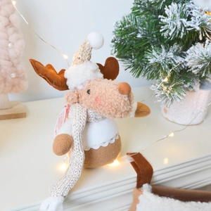 Plush Christmas reindeer figurine with sequined hat and silver scarf on snowy background