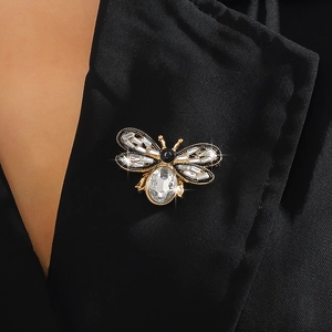 Close-up of a crystal bee brooch pinned on a black suit lapel with gold and diamond details