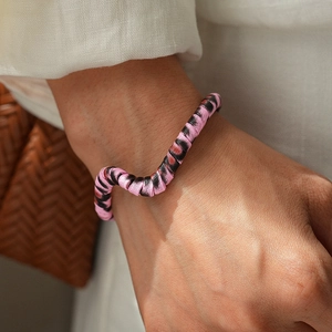 Macro detail of leopard print leather open bangle with pink and black twisted silk texture