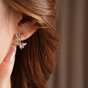 Macro shot of gold leaf branch earring with sparkling colorful zircon stones on model