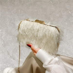 Detail of elegant off-white fringe evening clutch bag with gold chain and metal frame
