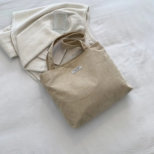 Detailed texture of light khaki corduroy tote bag with Fashion label on white fabric