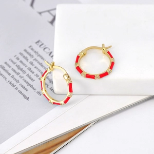 Close-up of red enamel bamboo hoop earrings with sparkling zircons on marble
