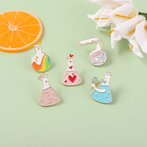 Detailed view of five creative enamel pins featuring heart and rainbow chemical flasks