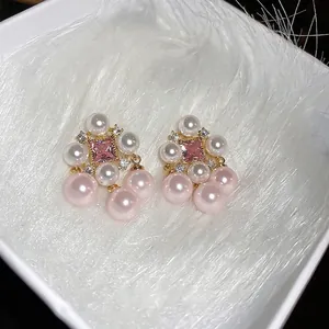 Elegant gold plated square pink zircon and pearl tassel earrings on white plush background