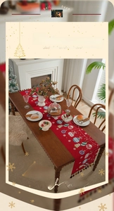 Detailed view of red Christmas table runner with festive prints and colorful tassels