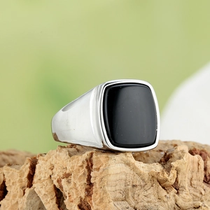 Close-up of silver titanium steel signet ring with black stone on a cork base