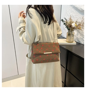 Detailed texture of brown corduroy shoulder bag featuring red strawberry embroidery
