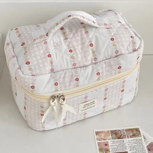 Detail of quilted makeup bag featuring pink checks, floral patterns and ribbon bows