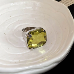 Macro shot of large emerald-cut yellowish-green gemstone set in a wide silver band ring