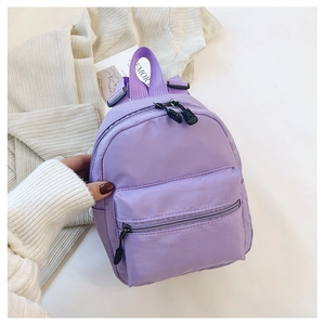 Macro detail of a purple mini nylon backpack featuring durable zippers and a front pocket