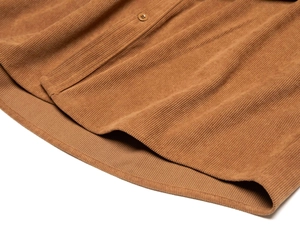 Dettaglio dell'orlo di una camicia di velluto a coste marrone con bottone coordinato