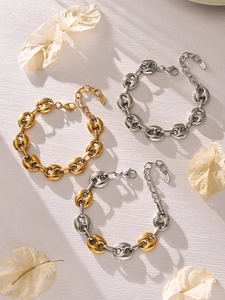 Vista dettagliata dei bracciali a chicco di caffè in oro, argento e bicolore su legno