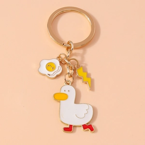 Detail of cartoon white duck keychain with fried egg and lightning charms on pink background