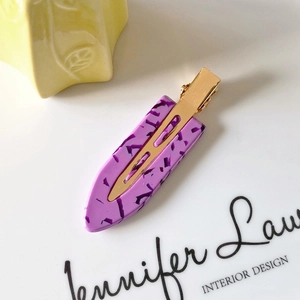 Detail of purple marble acetate hair clip with golden metal base on a white surface