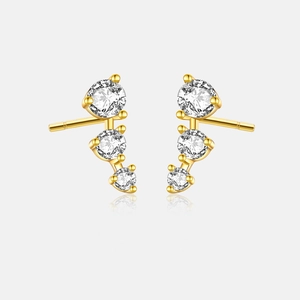 Close-up of golden three-stone curved earrings with sparkling round cubic zirconia