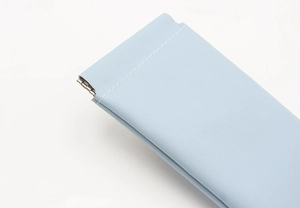 Close-up of light blue pebble grain leather glasses pouch with metal spring closure