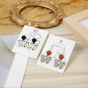 Detail of polka dot bow earrings with pearls against a vintage artistic backdrop