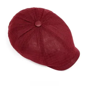 Top view of a burgundy newsboy cap showing woven texture and matching top button