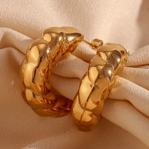 Close-up of thick 18K gold plated stainless steel twisted hoop earrings on beige fabric