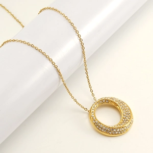 Collier en acier doré avec pendentif rond serti de zircons brillants sur fond blanc