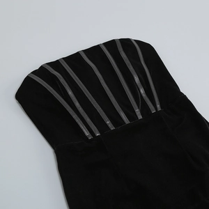 Close-up of black velvet corset dress featuring leather trim and asymmetrical hem detail