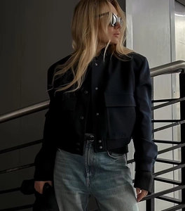 Detail of black wool jacket with stand collar, large pockets, and button-up front